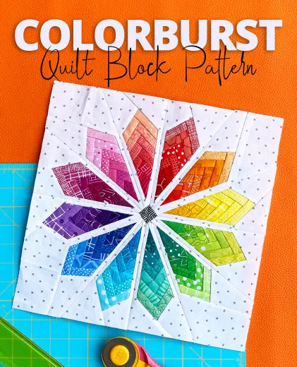 Foundation-Paper-Piecing-Quiltblock in Form eines achtzackigen Regenbogen-Blütensterns auf weißem gepunktetem Stoff, mit Rollschneider und Schneidematte.